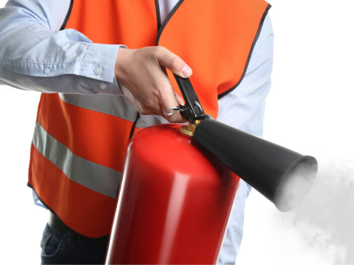 fire safety training - Worker using fire extinguisher on white background