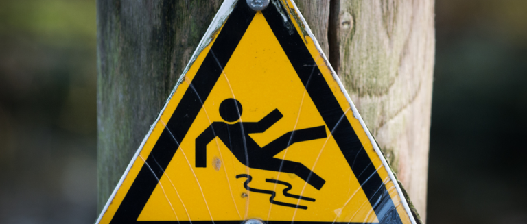 A "slippery surface" warning sign on a wooden post