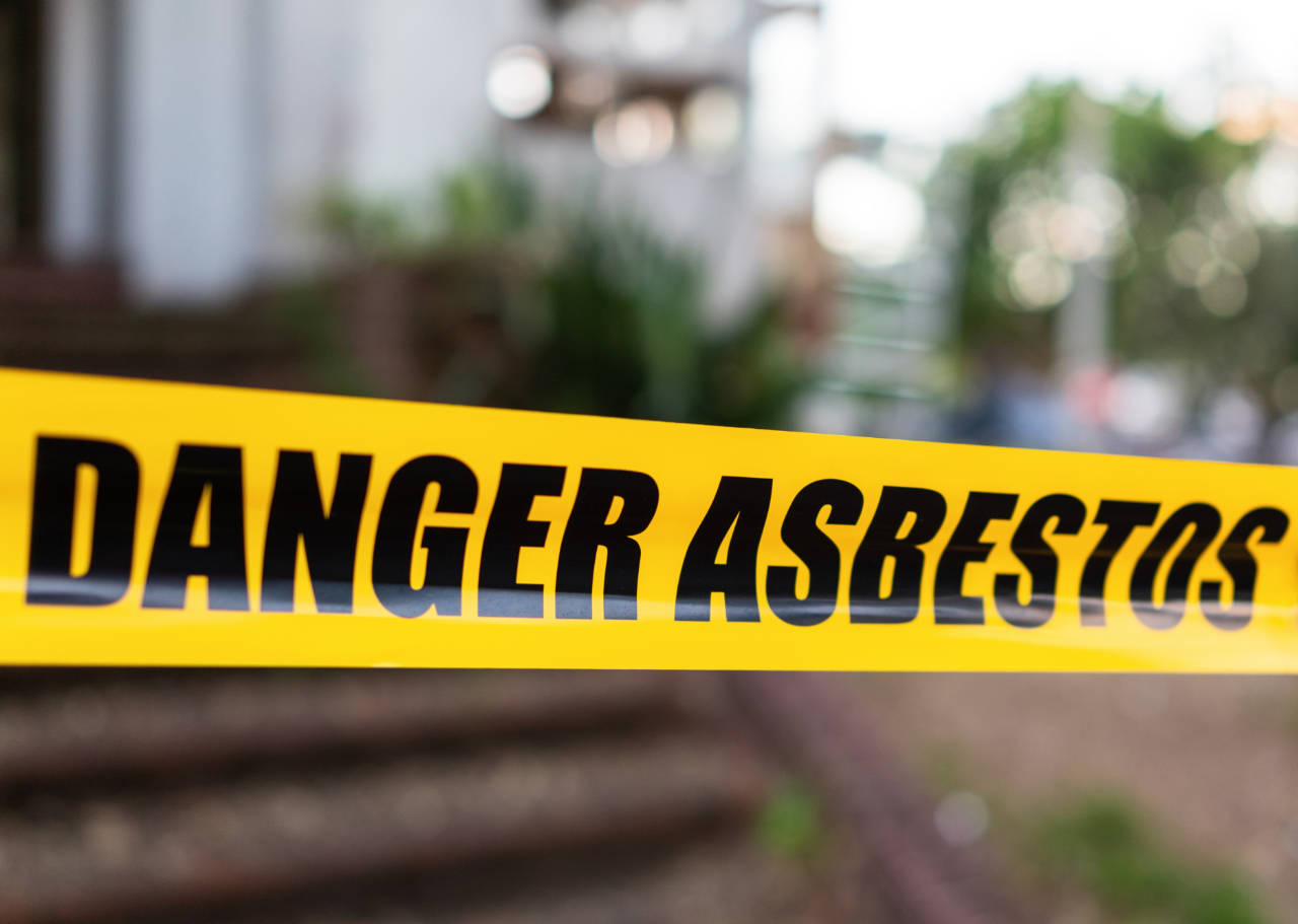 asbestos awareness – Yellow cordon tape warning of asbestos danger