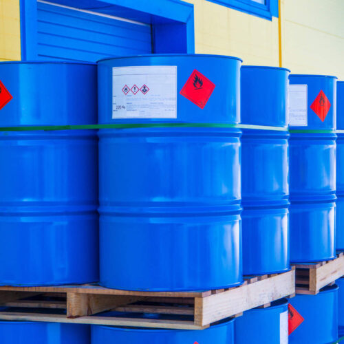 Large blue barrels on a pallet with hazard signs on them. Illustrates COSHH.