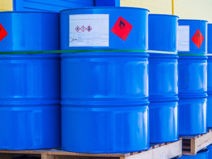 Large blue barrels on a pallet with hazard signs on them. Illustrates COSHH.