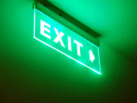 Photo of exit sign on a ceiling glowing green