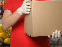 a person wearing gloves holding a box to illustrate safe manual handling