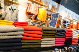 Inside a men's clothes shop with jumpers neatly piled and arranged.