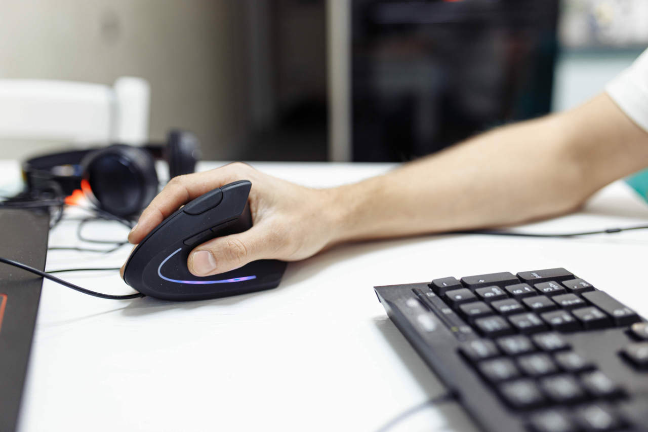 Office worker using ergonomic mouse to prevent RSI carpal tunnel syndrome