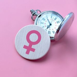 Stop watch and female symbol against a pink background