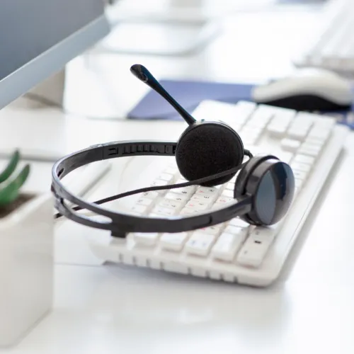 White keyboard with a headset placed on top to illustrate health and safety support service.