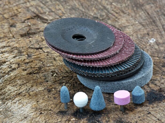 Stack of black, blue and maroon abrasive wheels on a bark background.