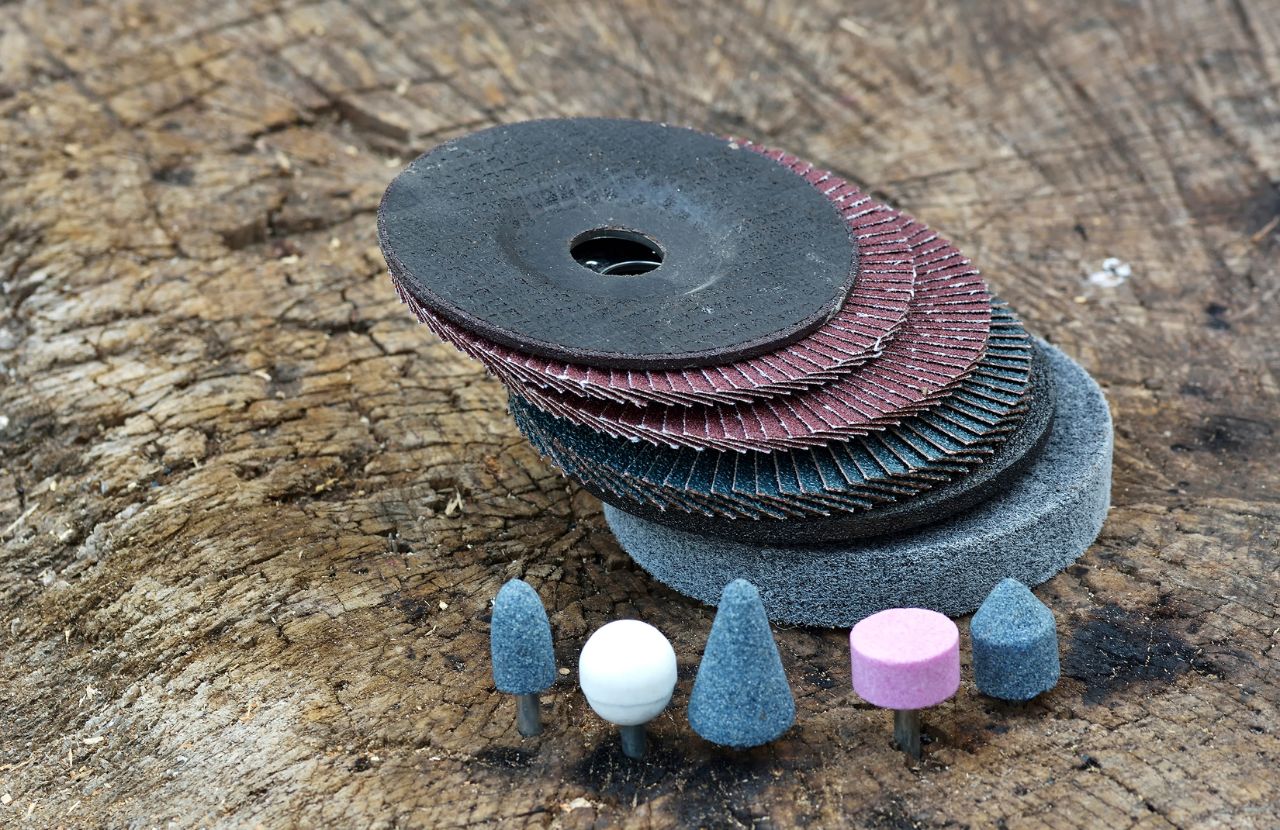 Stack of black, blue and maroon abrasive wheels on a bark background.