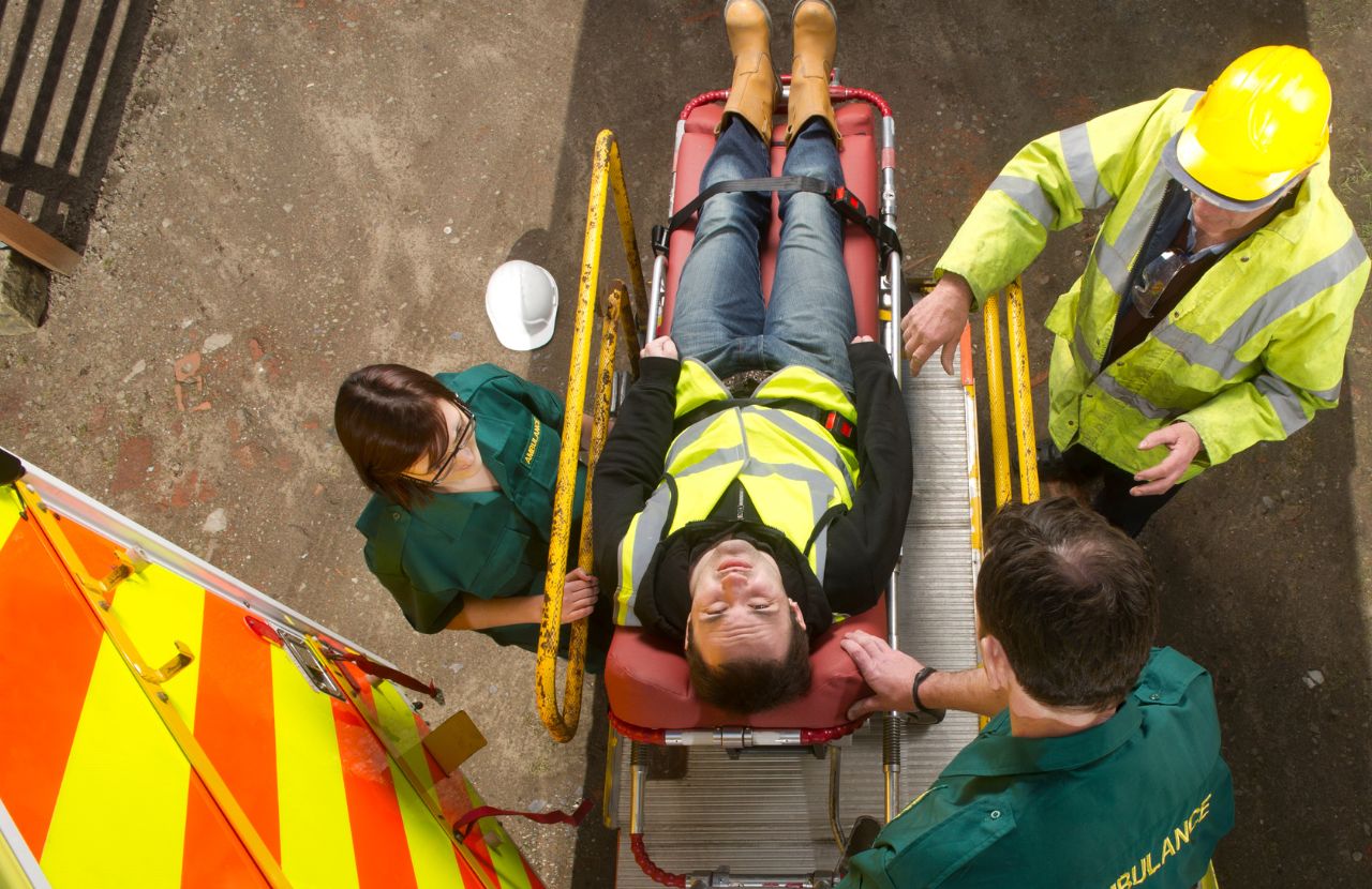 Close-up bird's eye view of man on stretcher on building site boarding an ambulance
