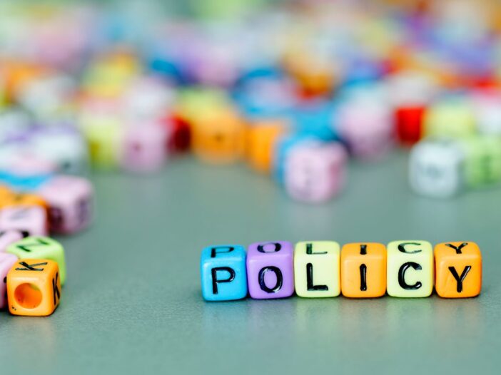 Coloured letter blocks displaying the word policy with random letter blocks scattered around