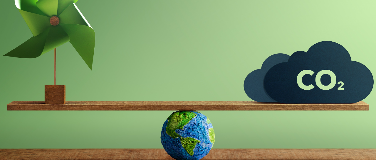 Environmental symbol of the globe beneath a seesaw balancing a paper windmill and a CO2 cloud