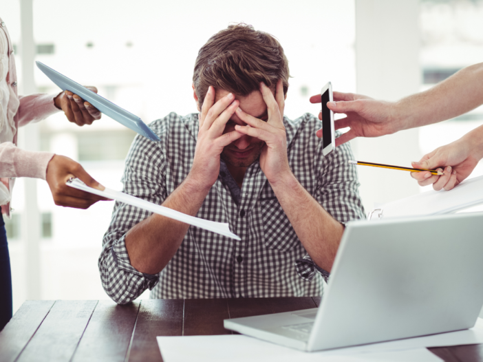 Man in office with excessive workload to illustrate workplace psychosocial risks.