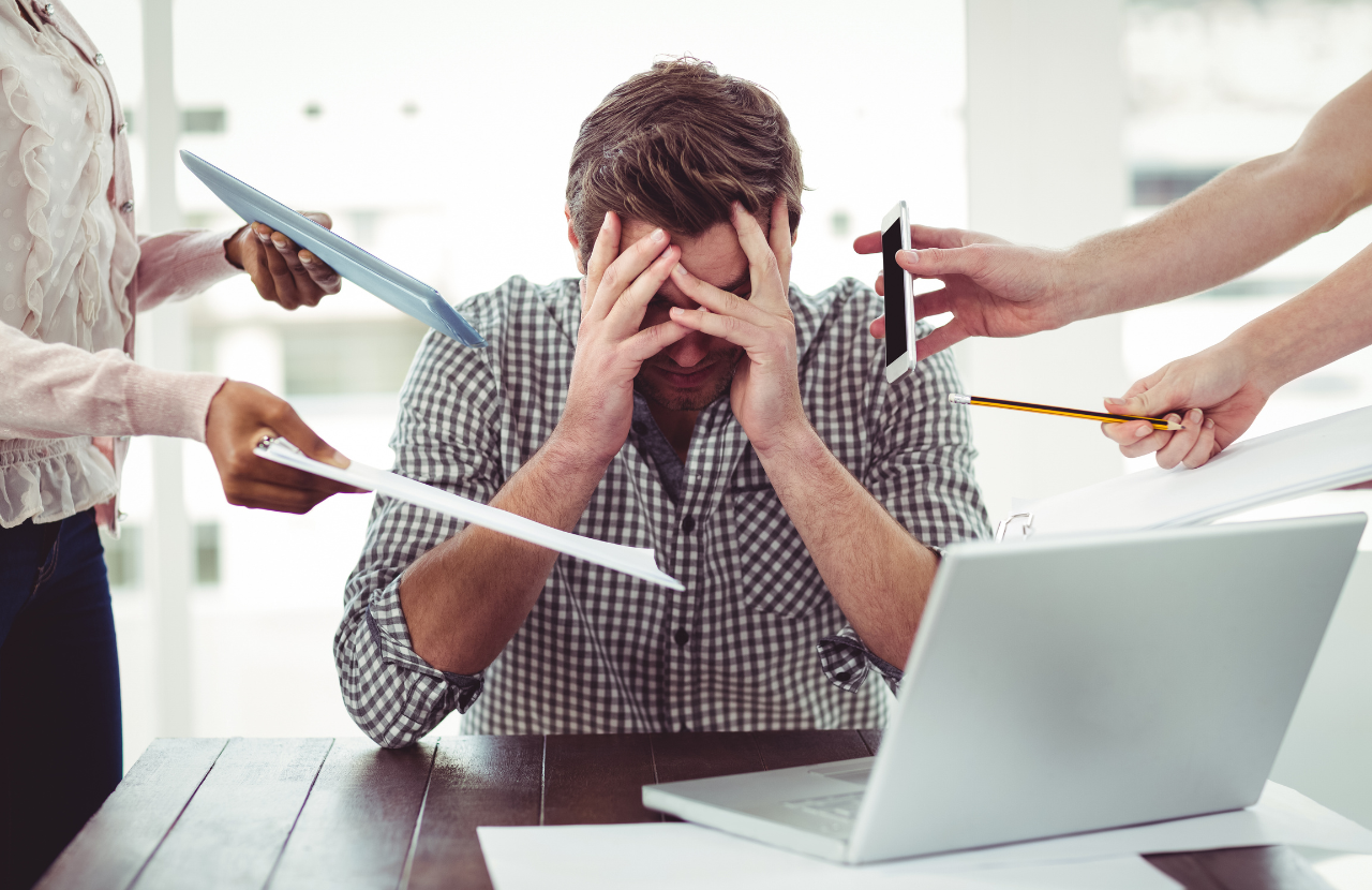 Man in office with excessive workload to illustrate workplace psychosocial risks.