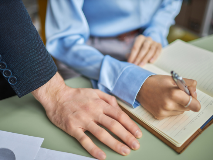 What is sexual harassment in the workplace? Illustrating a man's hand very close to a woman's hand as she works.