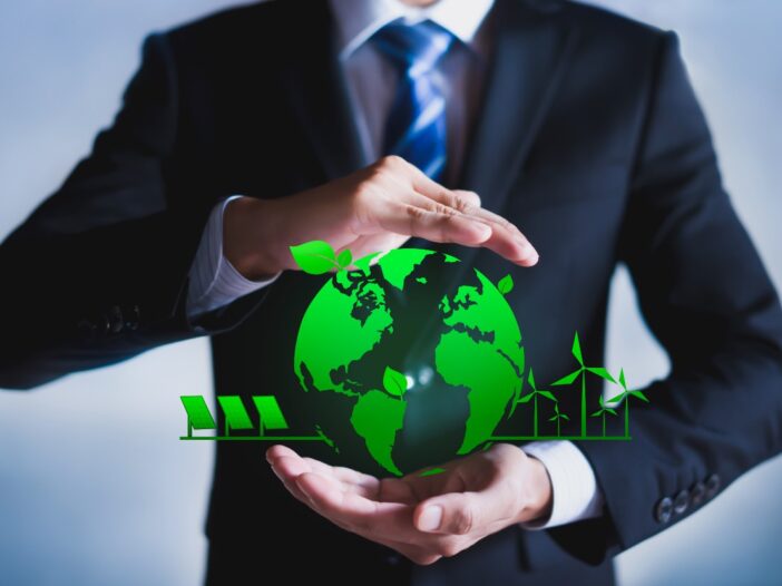 Man in suit holding a green symbol of the Earth with solar panels and leaves to symbolise ESG practices and awareness of the environment