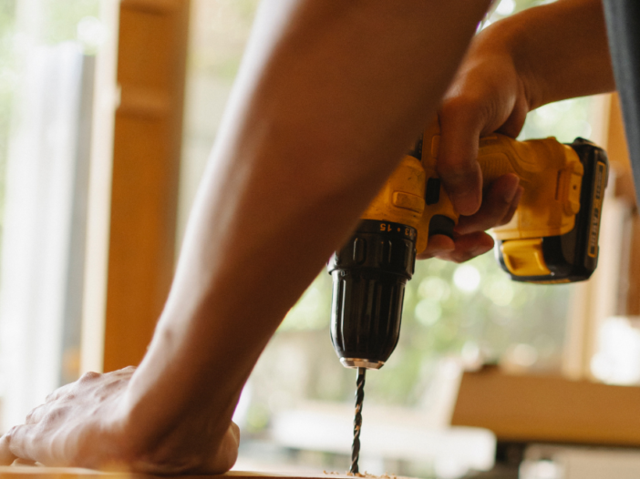 Man using drill to drill a hole in wood.