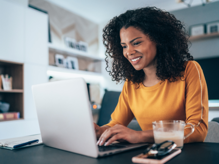 Woman working in comfortable office on laptop to illustrate hybrid workplace.