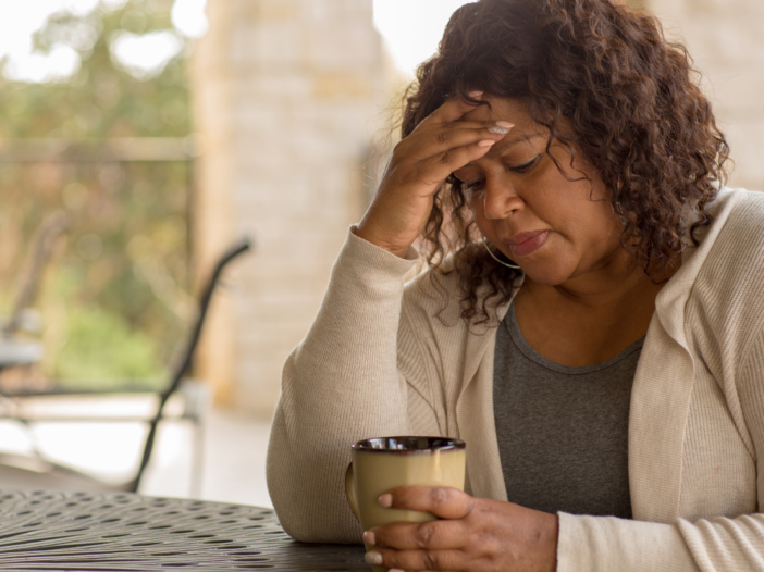Woman at work with head in hands to illustrate menopause policy template