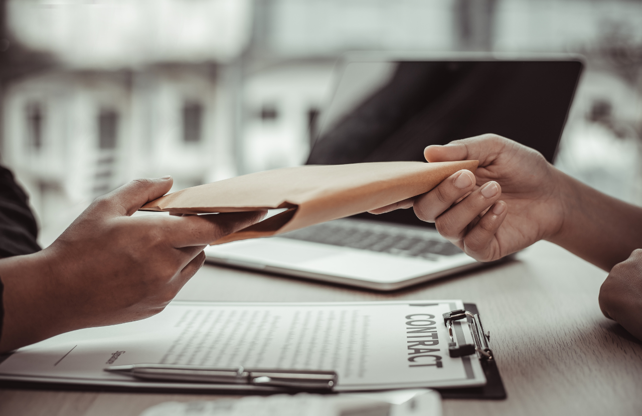 One person handing an envelope to another to demonstrate fraud.