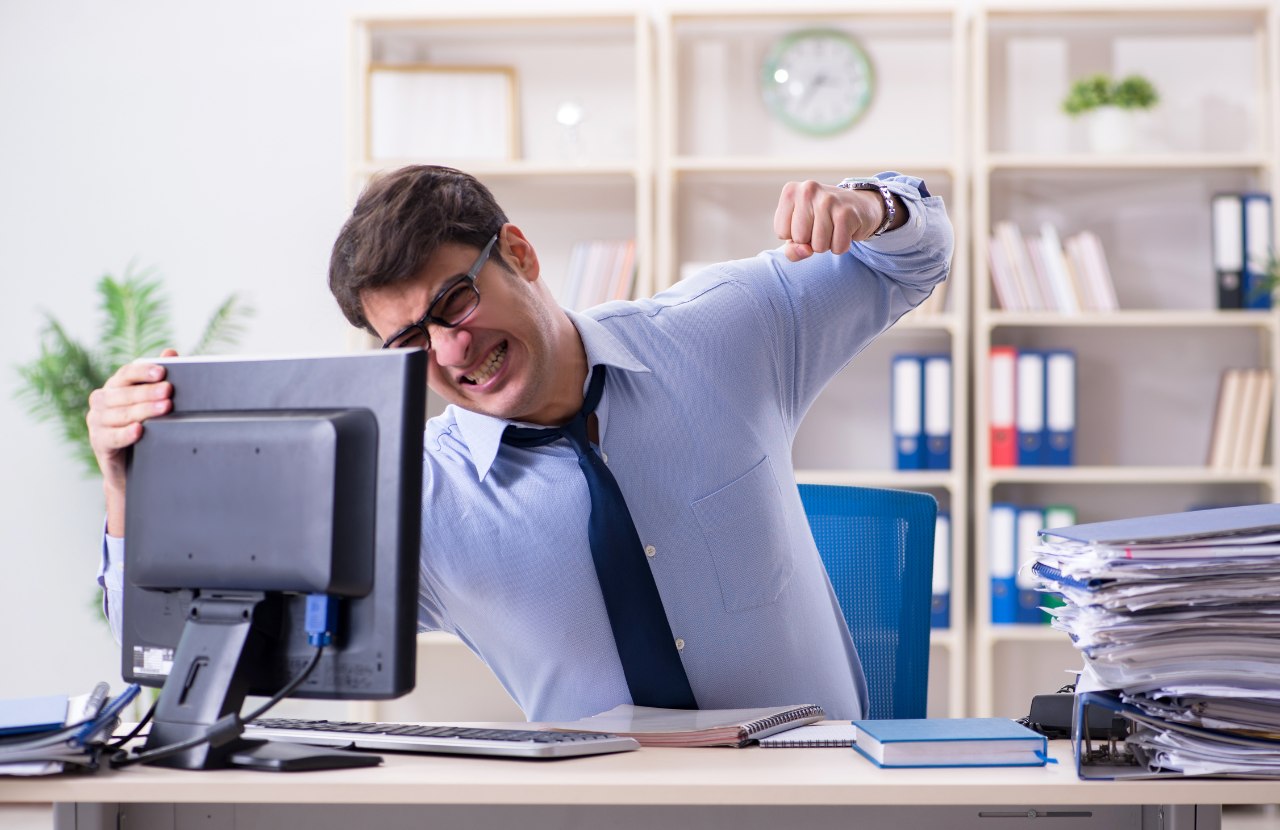 Man frustrated at work punching computer screen to illustrate gross misconduct
