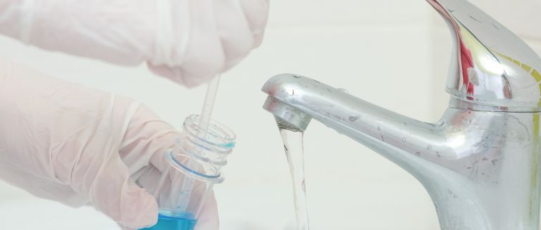 A pair of hands wearing latex gloves testing a tap for Legionella