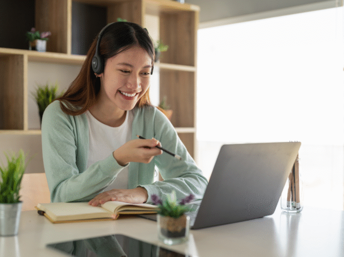 Woman at home engaging in eLearning on a laptop with a notepad in front of her