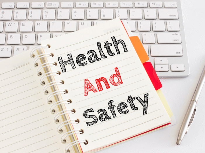 White keyboard with notebook on top that says 'health and safety' in large letters.