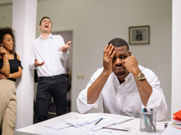 Image showing a man and woman laughing while another man is at his desk looking uncomfortable