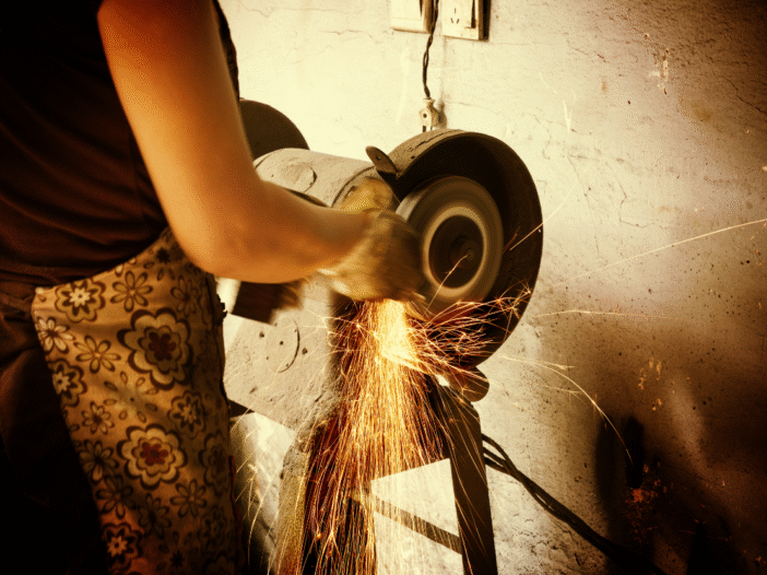 Woman in apron using an abrasive wheel