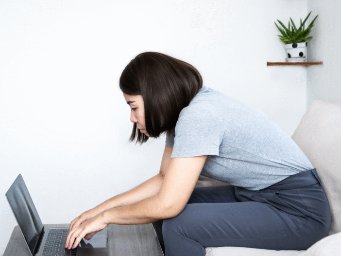 Woman sitting at a laptop with bad posture.