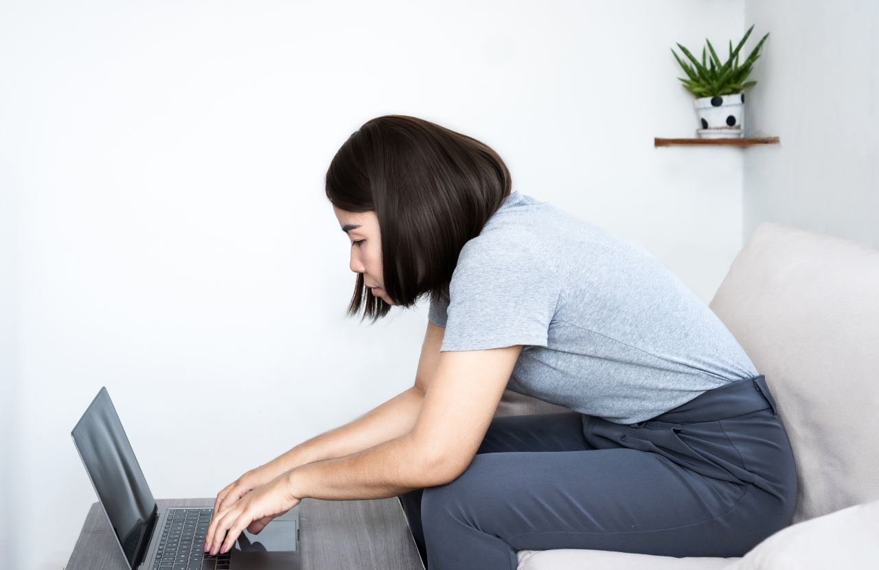 Woman sitting at a laptop with bad posture.