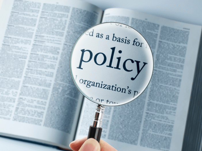 A book open with a magnifying glass highlighting the word 'policy'