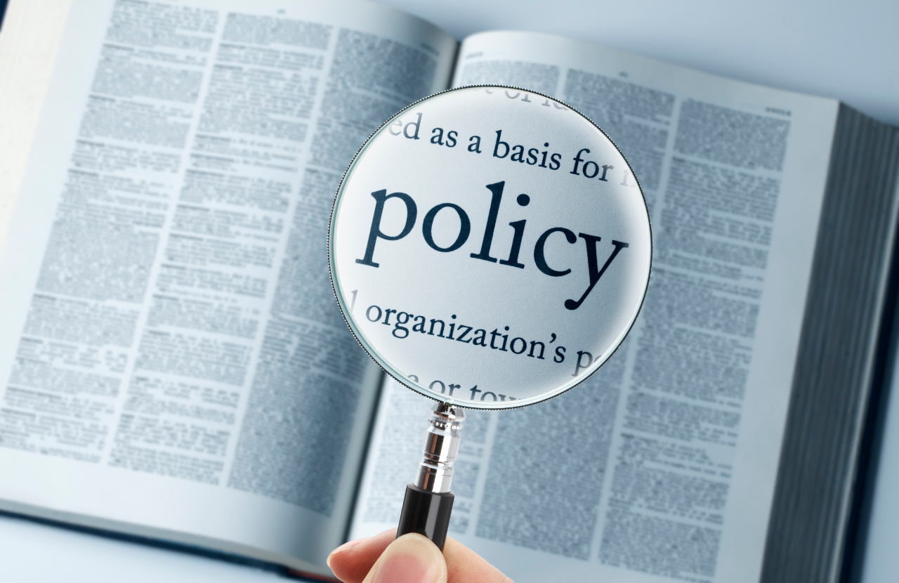 A book open with a magnifying glass highlighting the word 'policy'