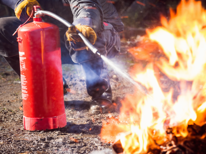 Firefighter putting out small fire with extinguisher