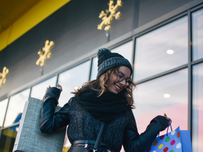 Happy woman carrying shopping backs to illustrate customer safety in retail stores