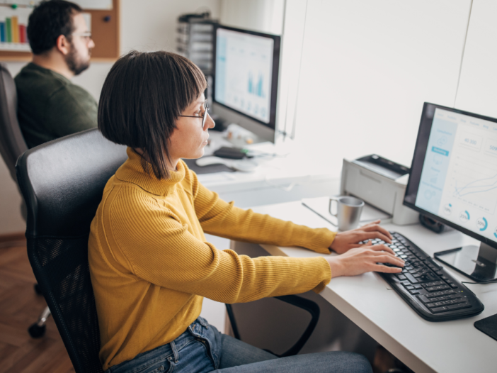 Close up of a man and a woman working at desktop computers in a comfortable office environment to illustrate principles of Workplace Health Safety & Welfare Regulations 1992