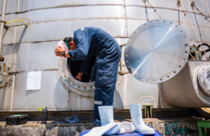 Worker in PPE climbing out of a confined space to illustration Confined Space Regulations 1997