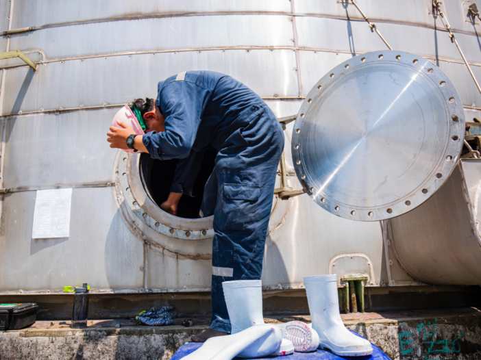 Worker in PPE climbing out of a confined space to illustration Confined Space Regulations 1997