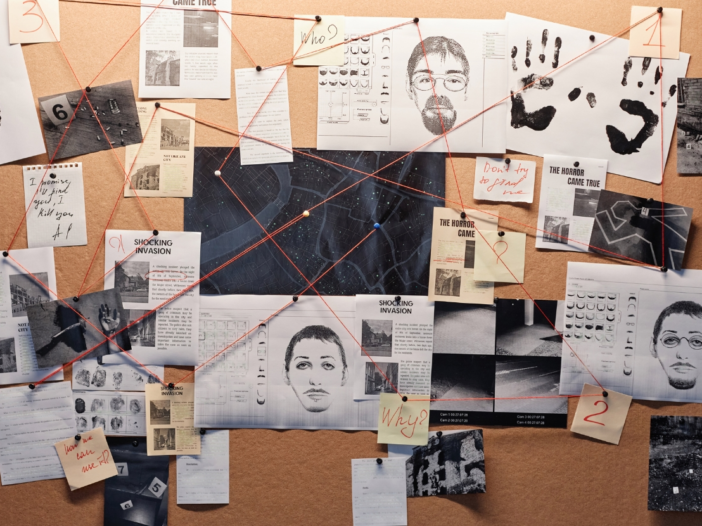 A corkboard in a police station, with red string linking sheets and photos of evidence