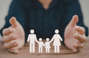 Picture of hands around cardboard figures of a family to represent safeguarding vulnerable groups act 2008