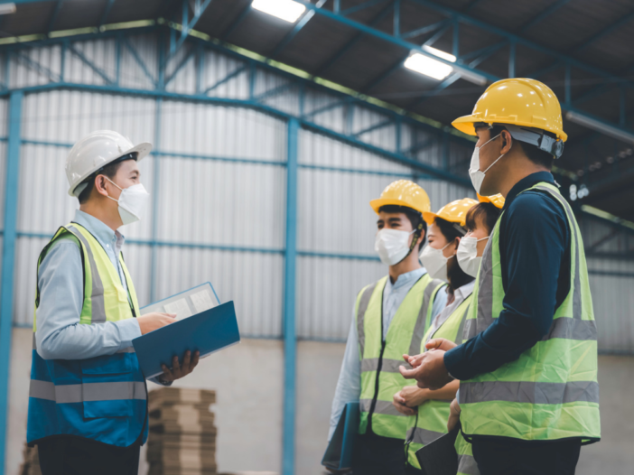 HSE investigation being carried out in a warehouse with four people in PPE and one holding a clipboard.